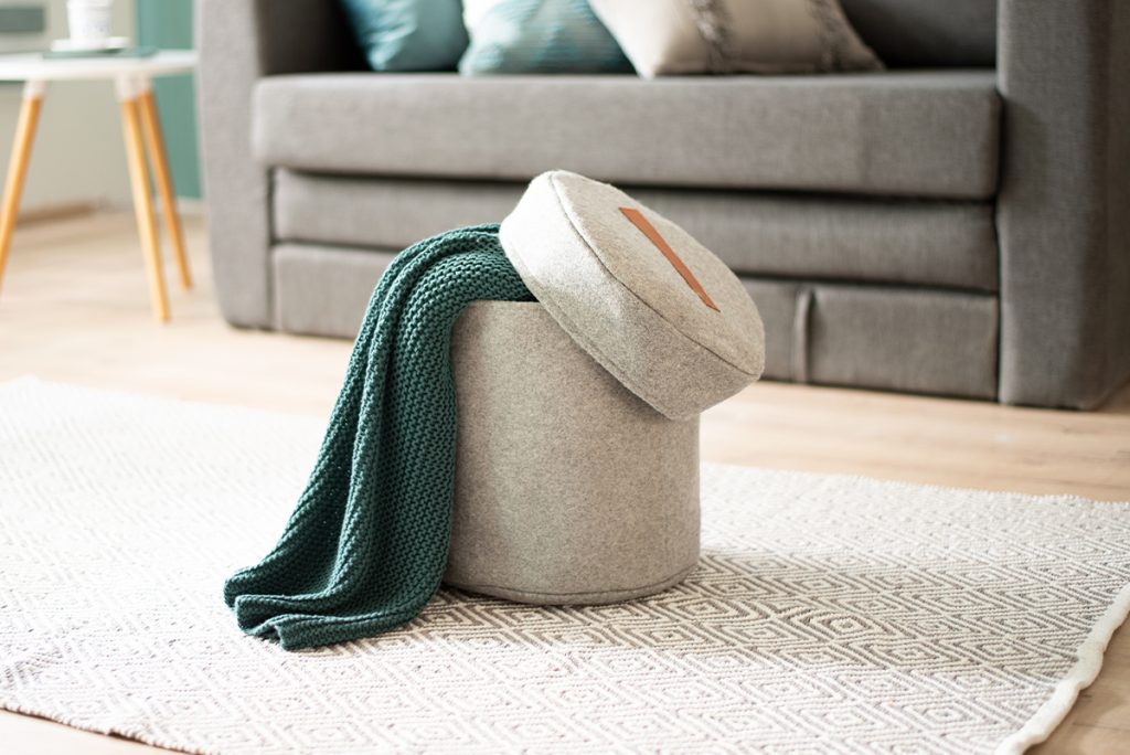 Rugmaker_Blog-Piece_Felt storage ottoman with green knitted throw on geometric rug in a bright Scandinavian minimalist l