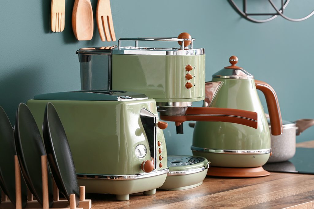 Rugmaker_Blog-Piece-SideImages_Electric kettle, coffee machine and toaster on wooden kitchen counter near green wall