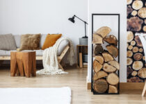 Rugmaker_Blog-Piece-Header_Wooden log texture wallpaper in cozy dining space of white open plan apartment with sofa, rug and tree stump accessories