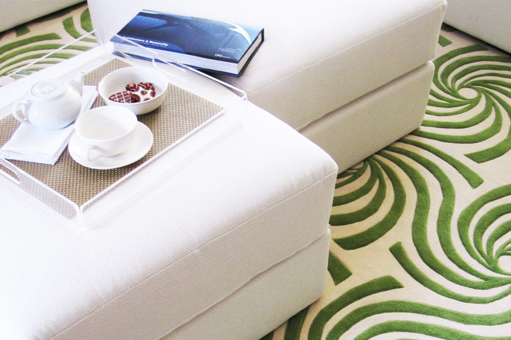 Rugmaker_Blog-Piece_An open concept living room viewed from above includes a sofa, rug, and tea with cookies. The space