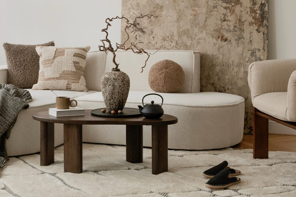 Rugmaker_Blog-Piece_Bright neutral living space with textured pillows, soft boucle seating, and a ceramic vase as the fo