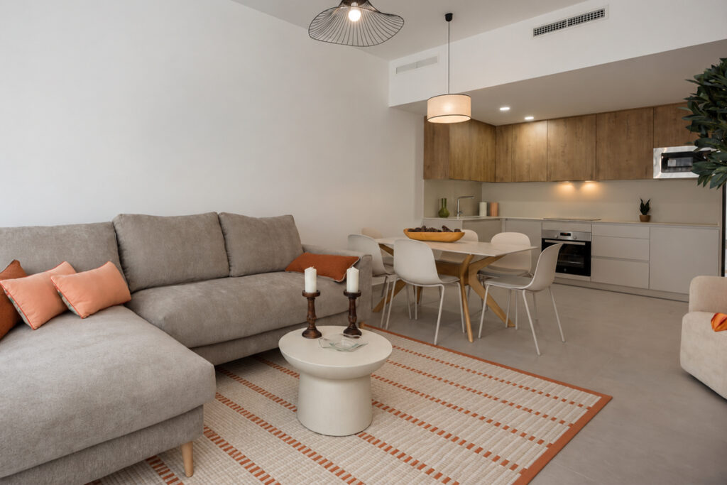 Rugmaker_Blog-Piece_Open-plan living and dining area with a grey sofa, dining table, pendant light, and kitchen beyond